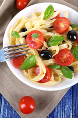 Spaghetti with tomatoes, olives and basil leaves