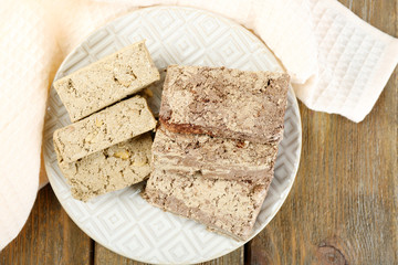 Two kinds of sunflower halva on plate, on wooden background
