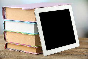 Fototapeta premium PC tablet and books on wooden table, on light background