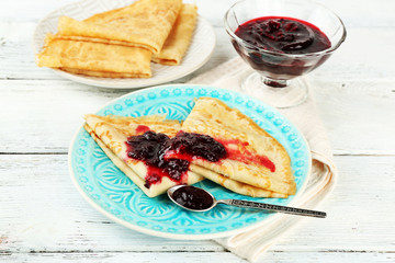 Plate of delicious pancakes with berry jam on wooden background