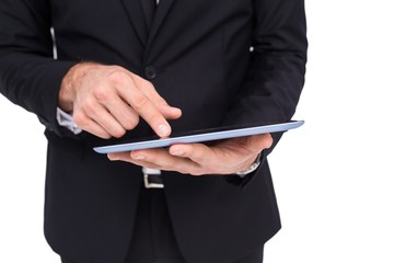 Mid section of a businessman touching digital tablet