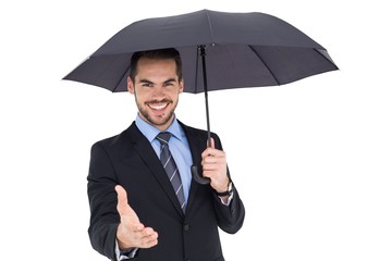 Happy businessman under umbrella offering handshake