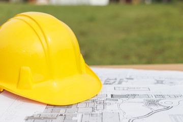 Close up Yellow safety helmet and floor plan drawings on the tab