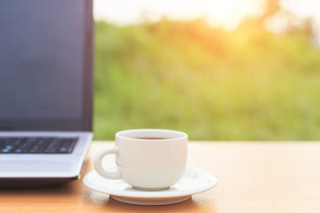 Close up coffee cup and laptop on the table in the morning