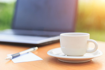 Close up coffee cup and laptop on the table in the morning