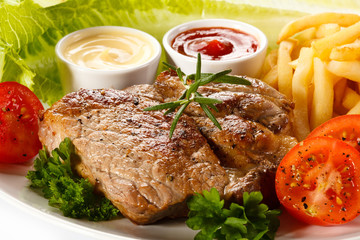 Barbecued steak, French fries and vegetables