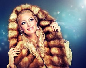 Winter model girl in luxury fur coat with a hood .