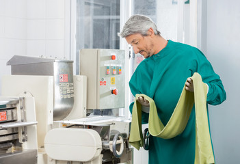 Chef Looking At Machine While Holding Spaghetti Pasta Sheet