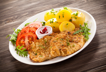 Fried pork chop, boiled potatoes and vegetable salad