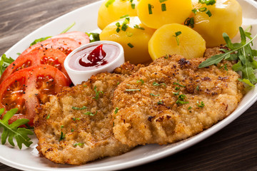 Fried pork chop, boiled potatoes and vegetable salad
