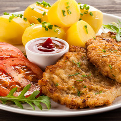 Fried pork chop, boiled potatoes and vegetable salad