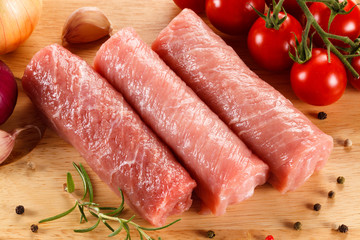 Raw pork chops on cutting board and vegetables