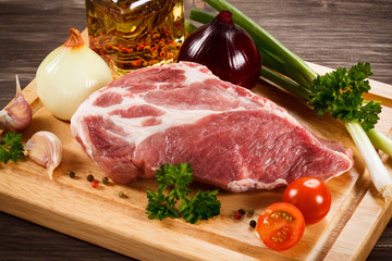 Raw pork on cutting board and vegetables