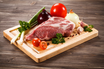 Raw pork on cutting board and vegetables