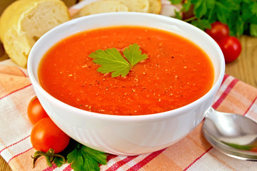 Tomato soup in bowl on napkin with bread