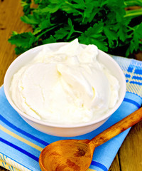 Yogurt in white bowl with greens on board