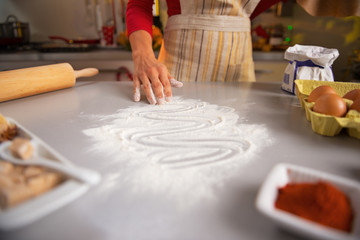 Closeup on young housewife drawing with flour on table