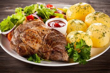 Barbecued steak, boiled potatoes and vegetable salad