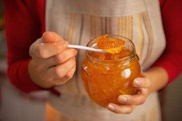 Closeup on young housewife holding homemade orange jam