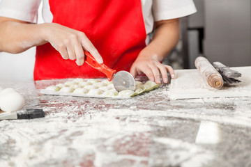 Female Chef Cutting Ravioli Pasta At Messy Counter