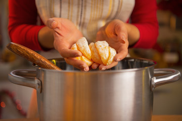 Closeup on young woman putting orange slices into pan