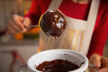 Closeup on young housewife making apple in chocolate glaze