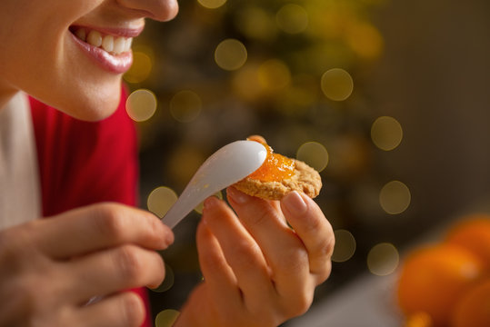 Closeup On Happy Young Woman Putting Orange Jam On Cookie