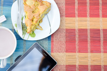 Piece of tasty biscuit apple pie, cup of hot cocoa and tablet