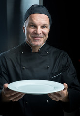 Chef in black uniform showing a plate