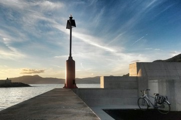 lighthouse,  dam and cycle against seascape sunset