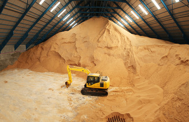 Excavator in a raw sugar storage - 73527625