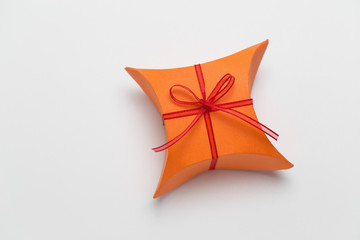 Orange gift box with decorative red ribbon