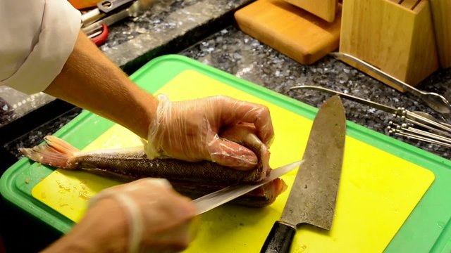 chef cooks food in the kitchen - chef slicing fish - closeup