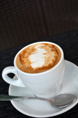 Cup of hot cappuccino on the black background