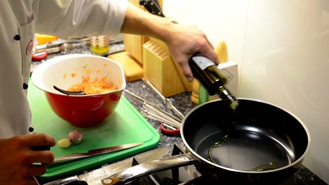 chef cooks food - chef pours oil in a frying pan