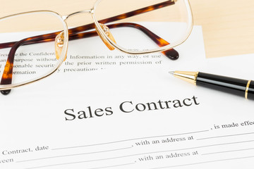 Sales contract document with glasses and pen
