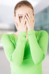 Attractive woman covering her face with both hands.