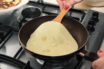 Woman's hands turning pancake by wooden trowel
