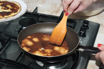 Pancake is frying in the pan at the gas-stove