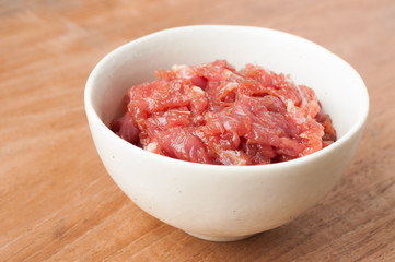 raw beef in white bowl on wooden background