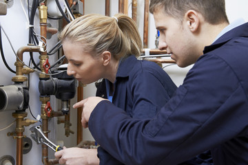 Female Trainee Plumber Working On Central Heating Boiler