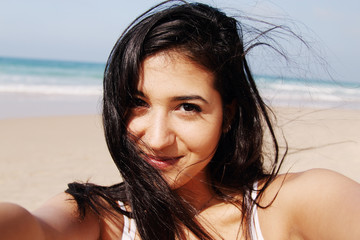 Beautiful girl smiling on the beach with the sand, sea and blue