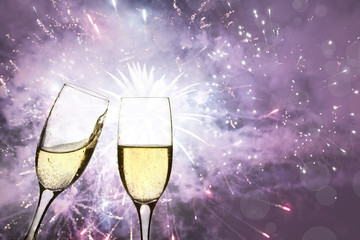Champagne glasses against holiday lights and fireworks