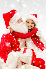 smiling girl hugging santa claus with gift at home