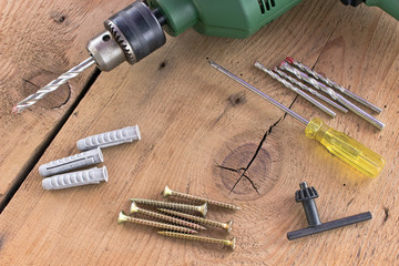 Drill and set of drill bits with screws on wooden background