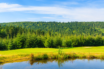 Lake on golf course in Bieszczady Mountains on sunny day, Poland