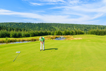 Obraz premium Mature man plays golf in Arlamow hotel, Bieszczady Mountains