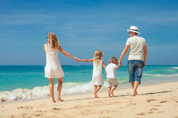 Happy  family  walking on the beach at the day time.