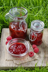 Fototapeta na wymiar Raspberry jam on wooden tray in the garden