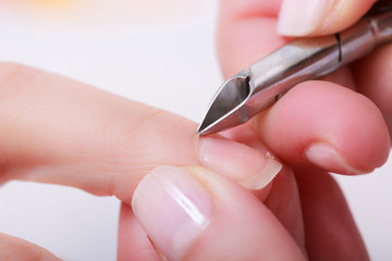 Beautician trimming cuticles of female client in beauty salon